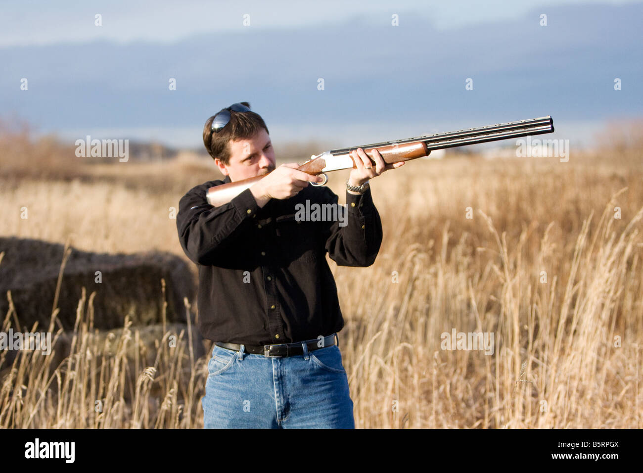 Mann schießen Schuss Pistole in einem Feld mit hohe Gräser. Stockfoto