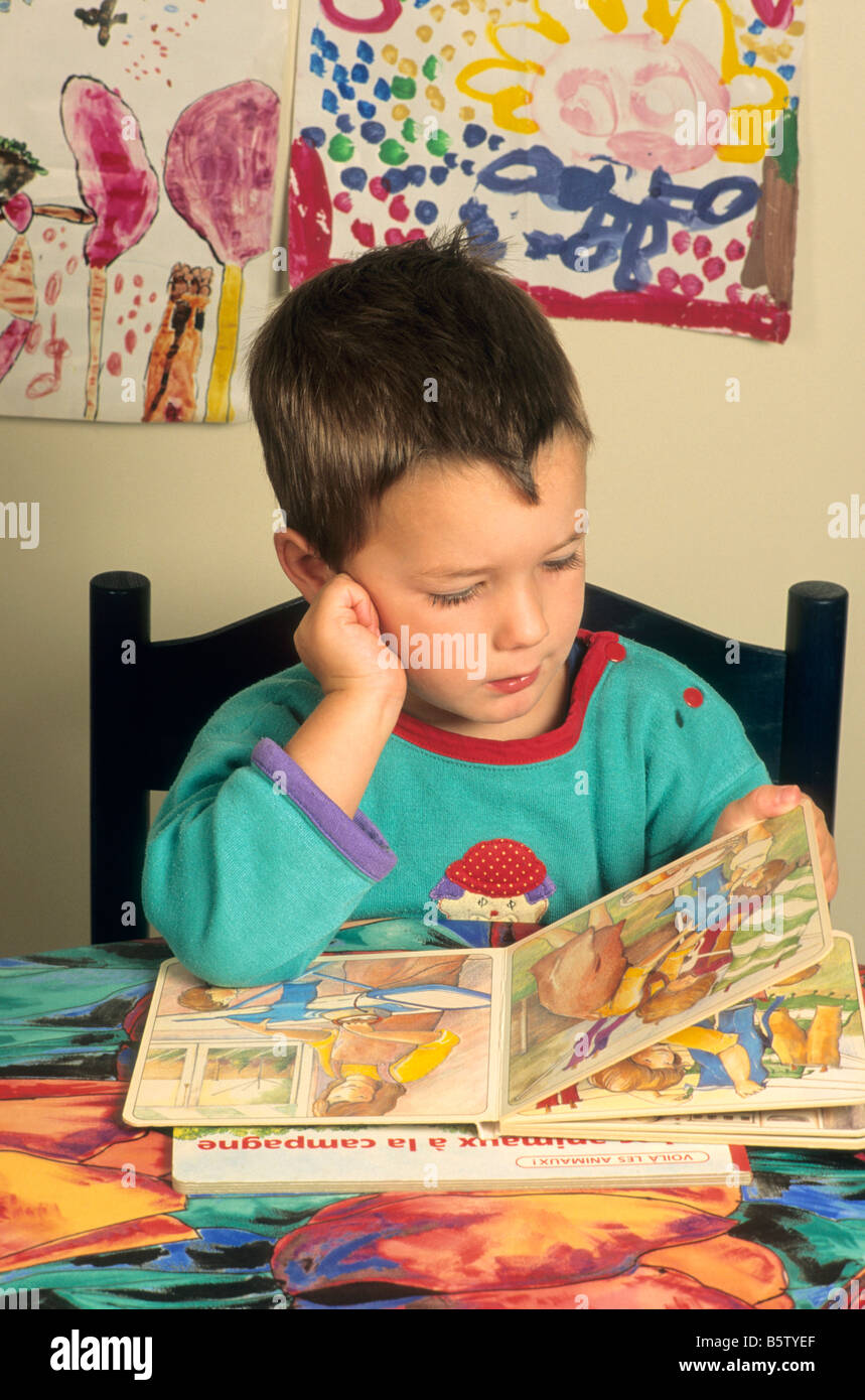 Kleiner Junge, ein Buch auf dem Küchentisch Stockfoto