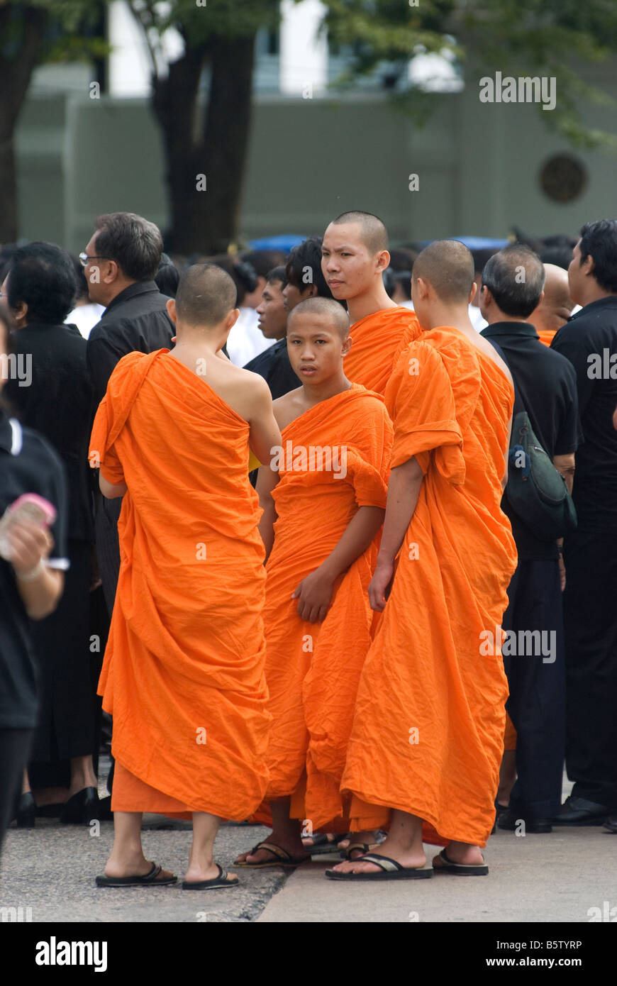 Trauernden gekleidet in schwarz und Mönche in ihren traditionellen orange Outfits beobachten die Prozession für die königliche Zeremonie der Feuerbestattung Stockfoto