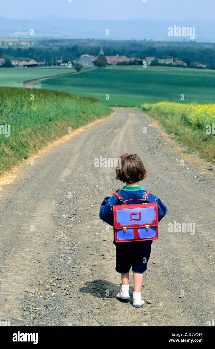 Kleines Mädchen zu Fuß entlang einer Landstraße gonna die Dorfschule in der Landschaft Stockfoto
