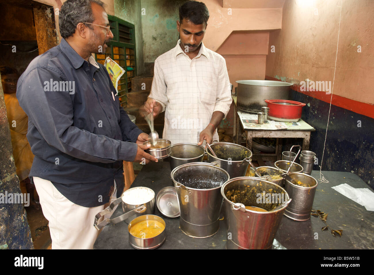 Ein Mann füllt seine Brotzeittasche Tiffin aus einer Straßenseite Shop in Pondicherry, Indien. Stockfoto