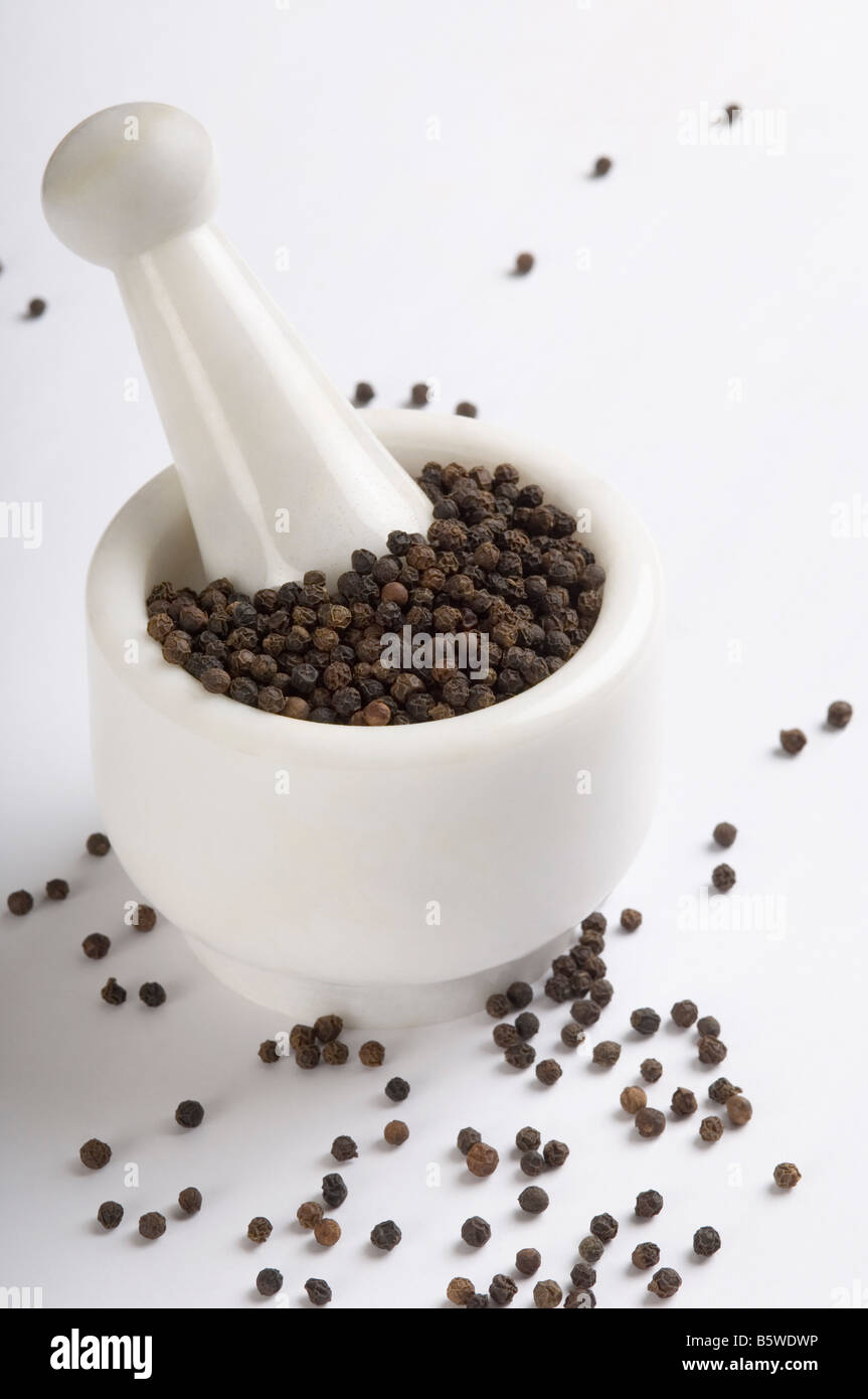 Schwarze Pfefferkörner im Mörser mit Stößel Stockfoto