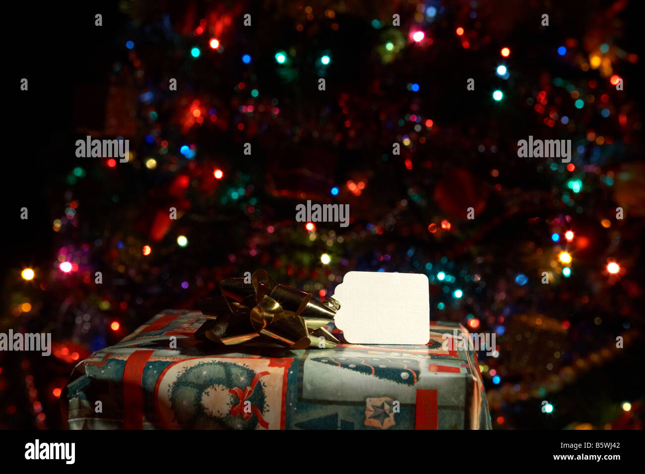 Spitze der verpackte Weihnachtsgeschenk mit Namensschild vor Weihnachtsbaum Stockfoto