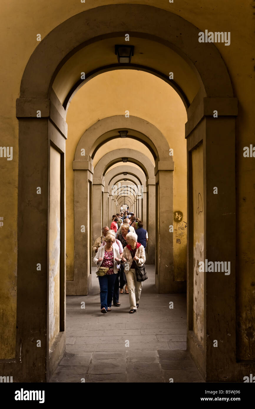 Touristen zu Fuß durch eine Reihe von Bögen entlang des Arno-Flusses in der Nähe von Ponte Vecchio Florenz Italien Stockfoto