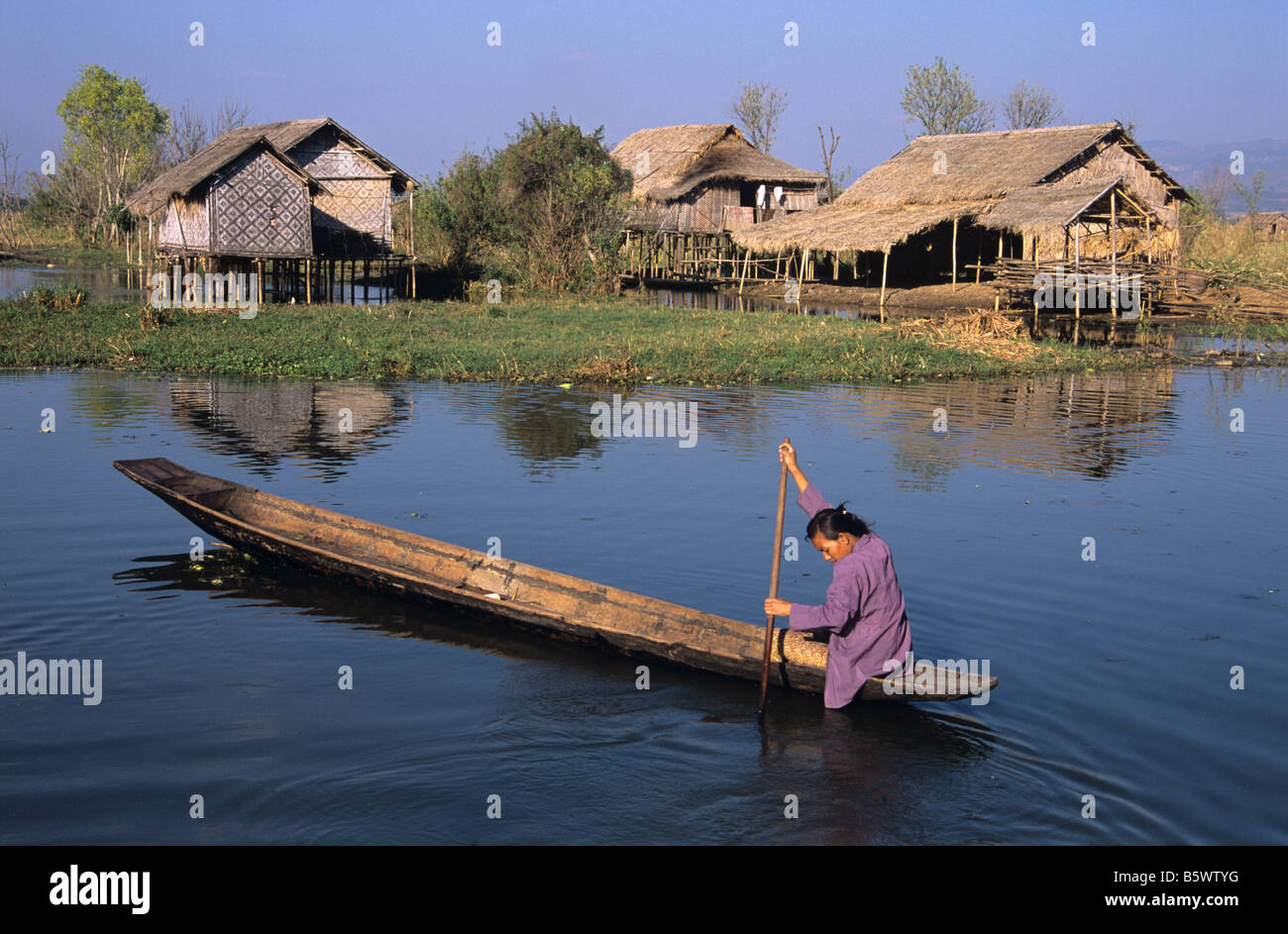 Eine burmesische Frau Kanus durch ein Stelzenläufer Dorf aufgewachsen auf Pilotis, Inle-See, Burma bzw. Myanmar Stockfoto