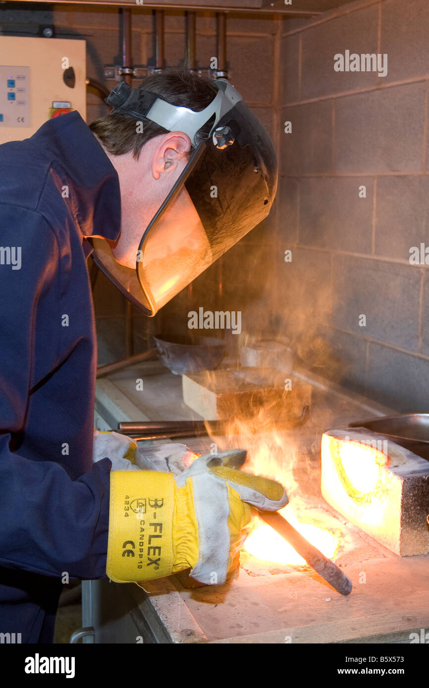 Arbeiter bei einem Recyclinghof Proben in einem Ofen schmelzen steel Stockfoto