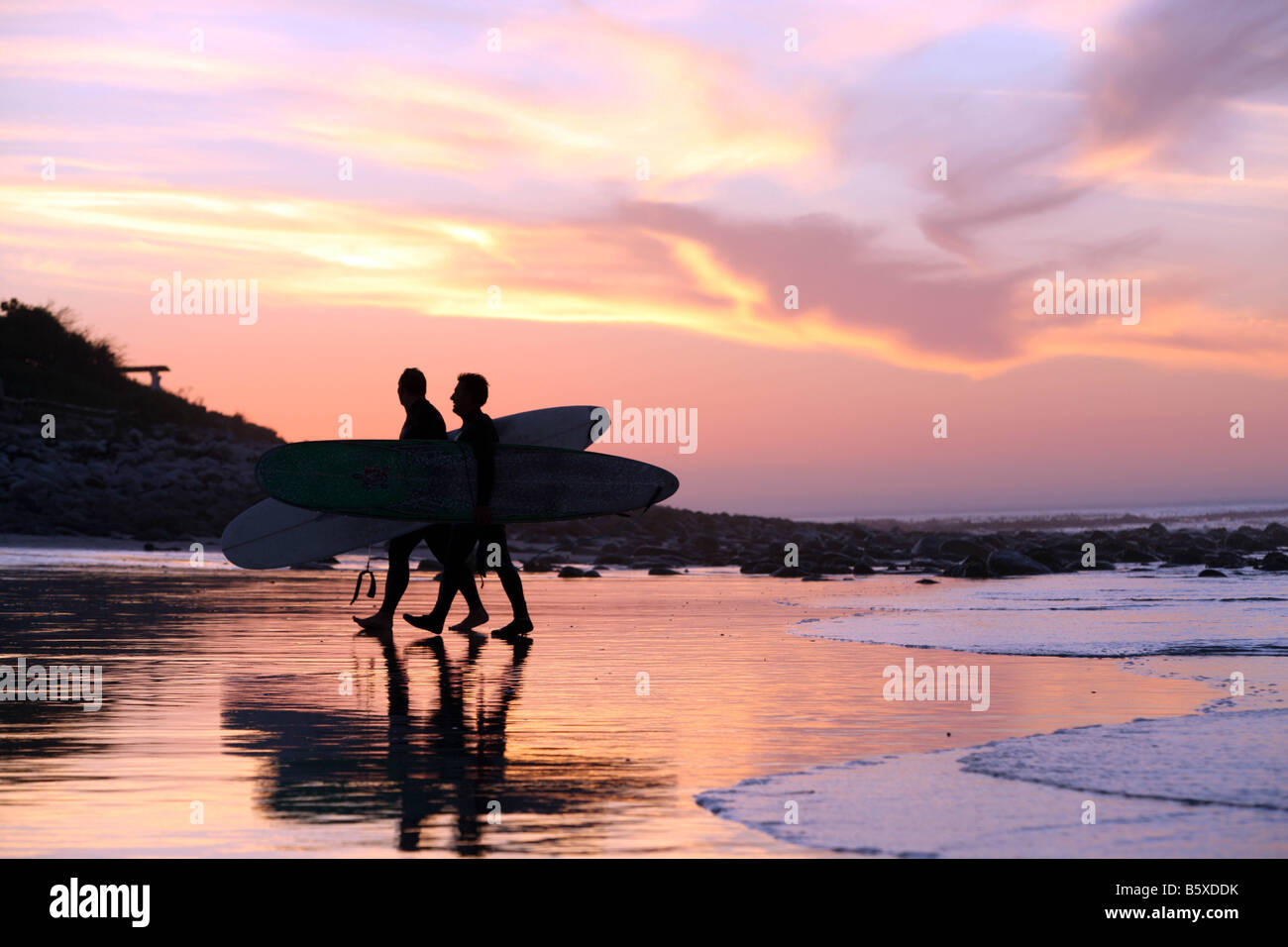 Zwei Surfer gehen Sie Long Beach in Kommetjie Südafrika während des Sonnenuntergangs März 2008 Stockfoto