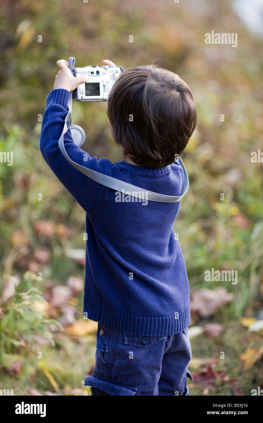 3 Jahre alter Junge sieht eurasischen kaukasischen barfuß im Herbst trägt einen blauen Pullover mit einer Digitalkamera Stockfoto