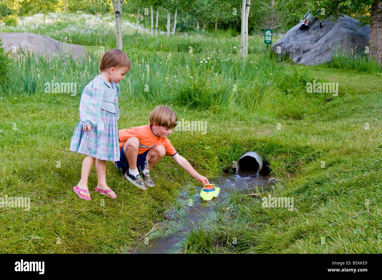 Kinder schweben eine Boot in einem Stream auf der David-Karetsky-Musik-Wiese beim Aspen Music Festival in Aspen, Colorado, USA. Stockfoto