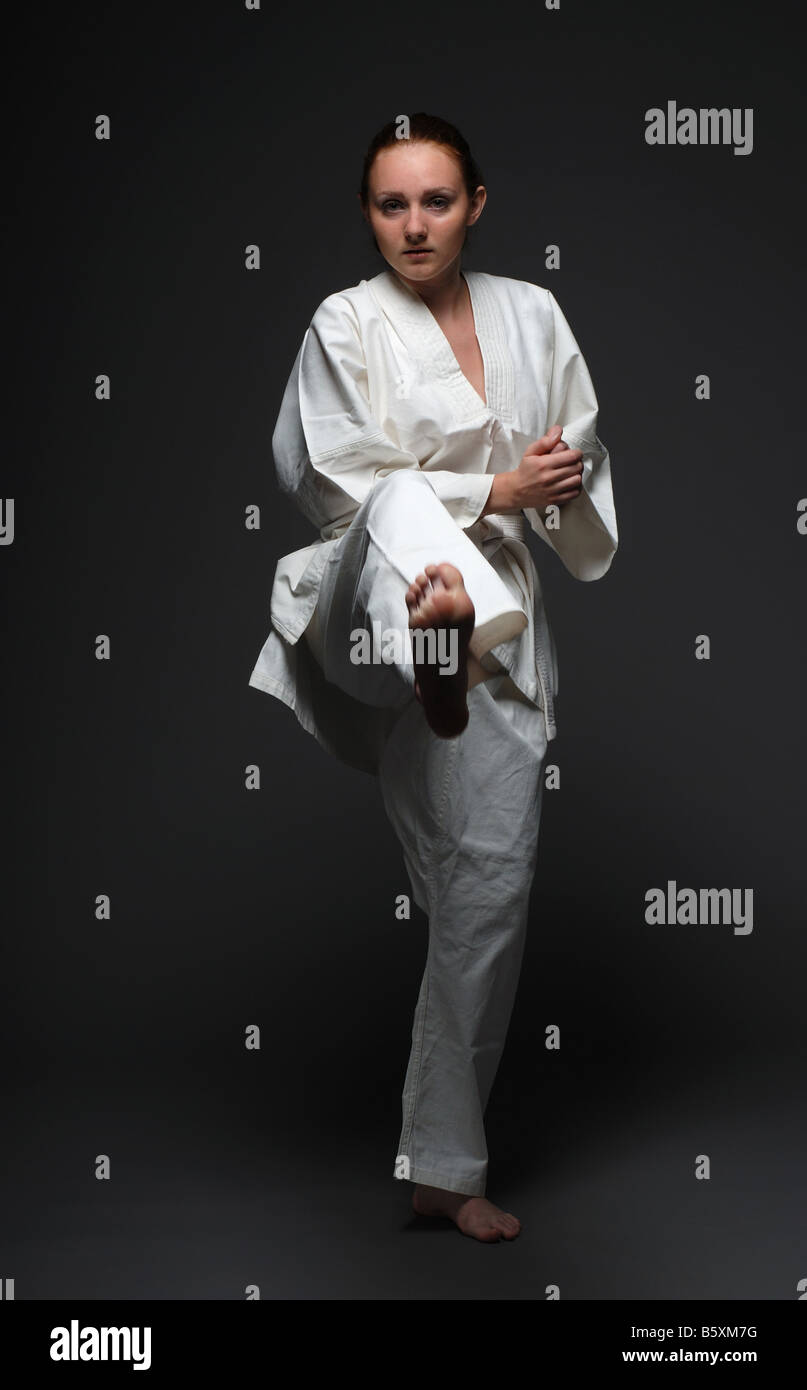 Mädchen in weißen Uniform wirft vorwärts rechtes Bein den dunklen Hintergrund Stockfoto