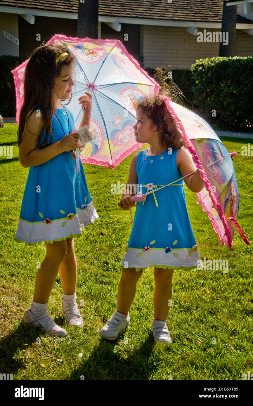 3 und 5 Jahre alten Schwestern Sonnenschirme zu verwenden, um im heißen California Sunshine MODELLFREIGABE kühl Stockfoto