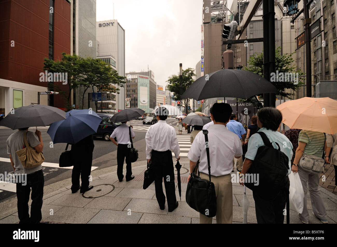 Fußgänger mit Sonnenschirmen. Einkaufsviertel Ginza, Chuo-Ku. Tokyo. Japan Stockfoto