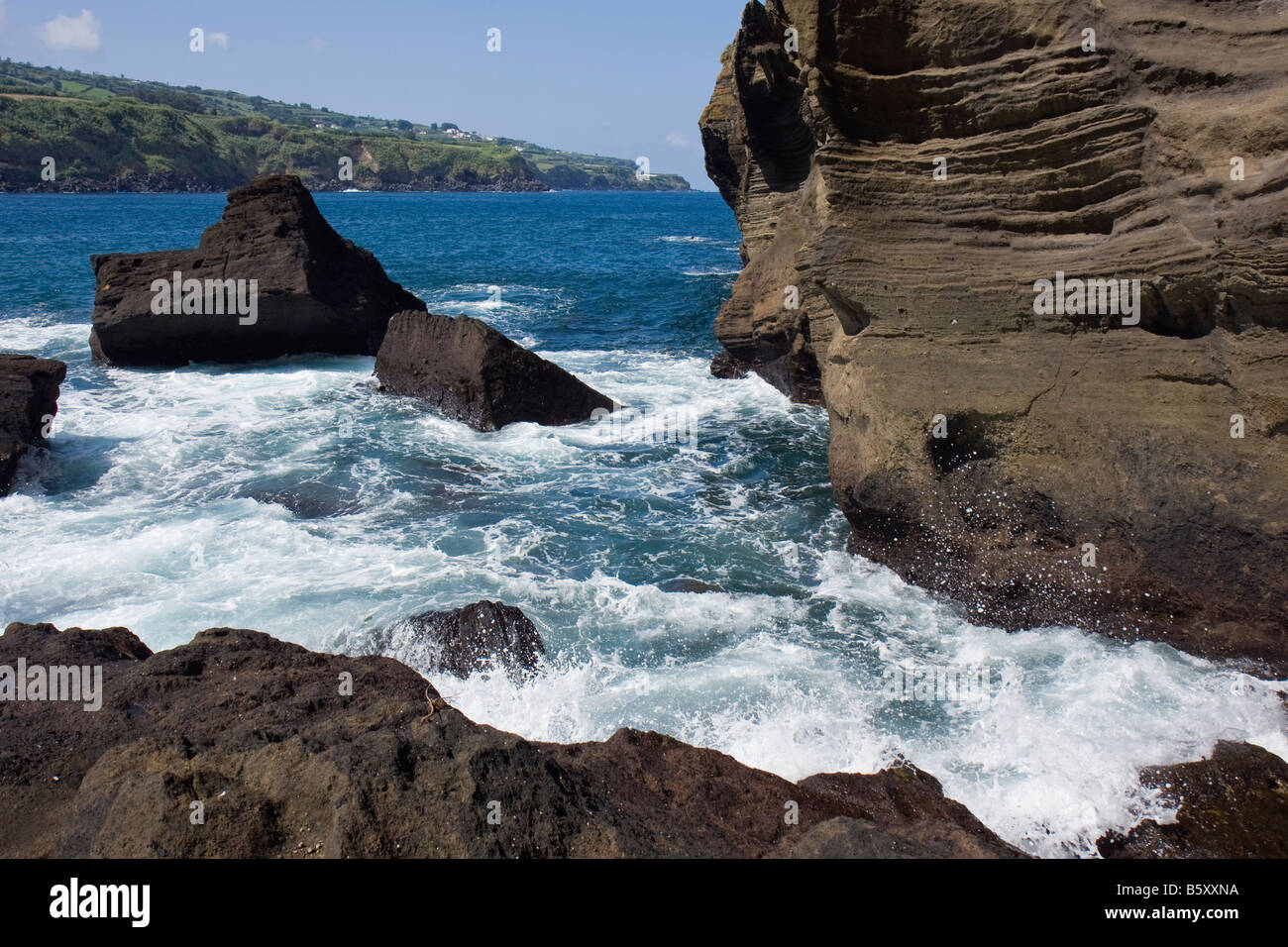 Ausgewaschene Felsen und Wellen in dem kleinen Fischerdorf Hafen Porto de Pesca Capelas São Miguel Azoren Stockfoto