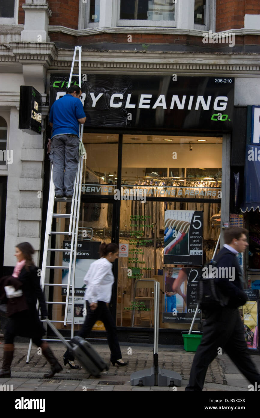 Reinigung der Reinigungsmittel chemische Reinigungswerkstatt das Schild im Zentrum von London mit einem Mann auf der Leiter gereinigt Stockfoto