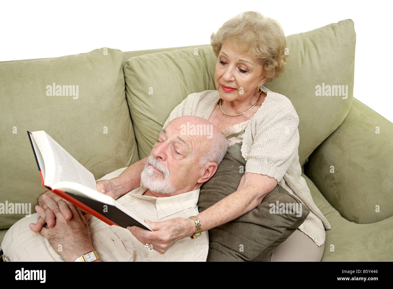 Ein senior Mann nehmen ein Nickerchen am Nachmittag, während seine Frau ihm weißer Hintergrund liest Stockfoto