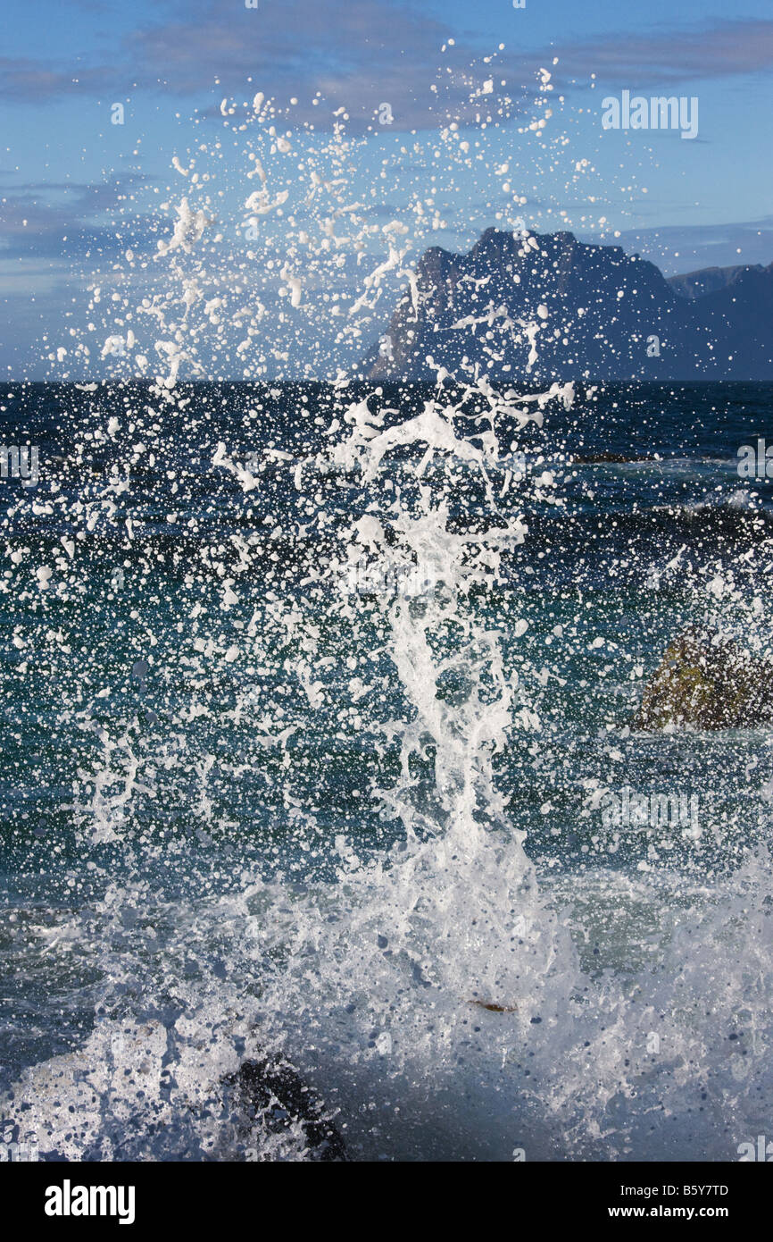 Spray fliegen, aus den Felsen am Myrland Lofoten-Inseln Norwegen mit Meer und schroffen Klippen im Hintergrund Stockfoto