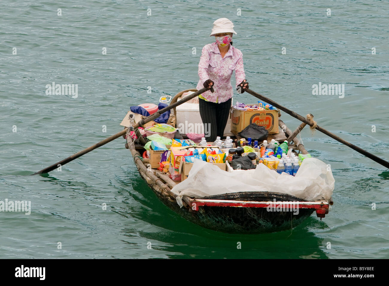 Frau mit ihren Produkten aus ein kleines Ruderboot in Halong Bucht, Vietnam Stockfoto