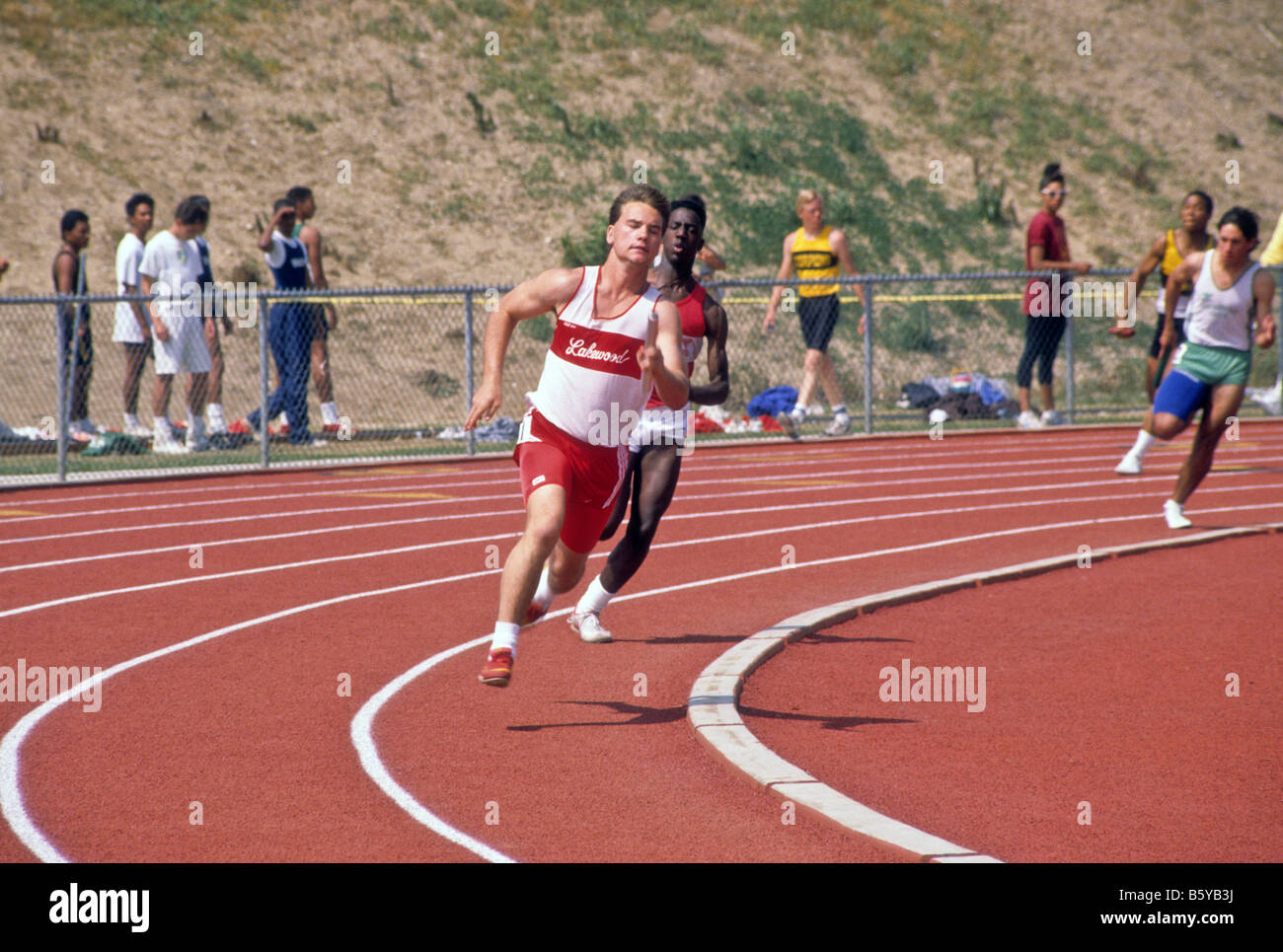 Highschool-Athleten nehmen die Kurve der Strecke während der Rennen auf der Strecke treffen Stockfoto