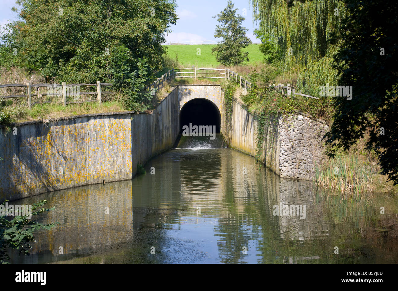 Stream läuft unter Tunnel Brücke in einen See Stockfoto