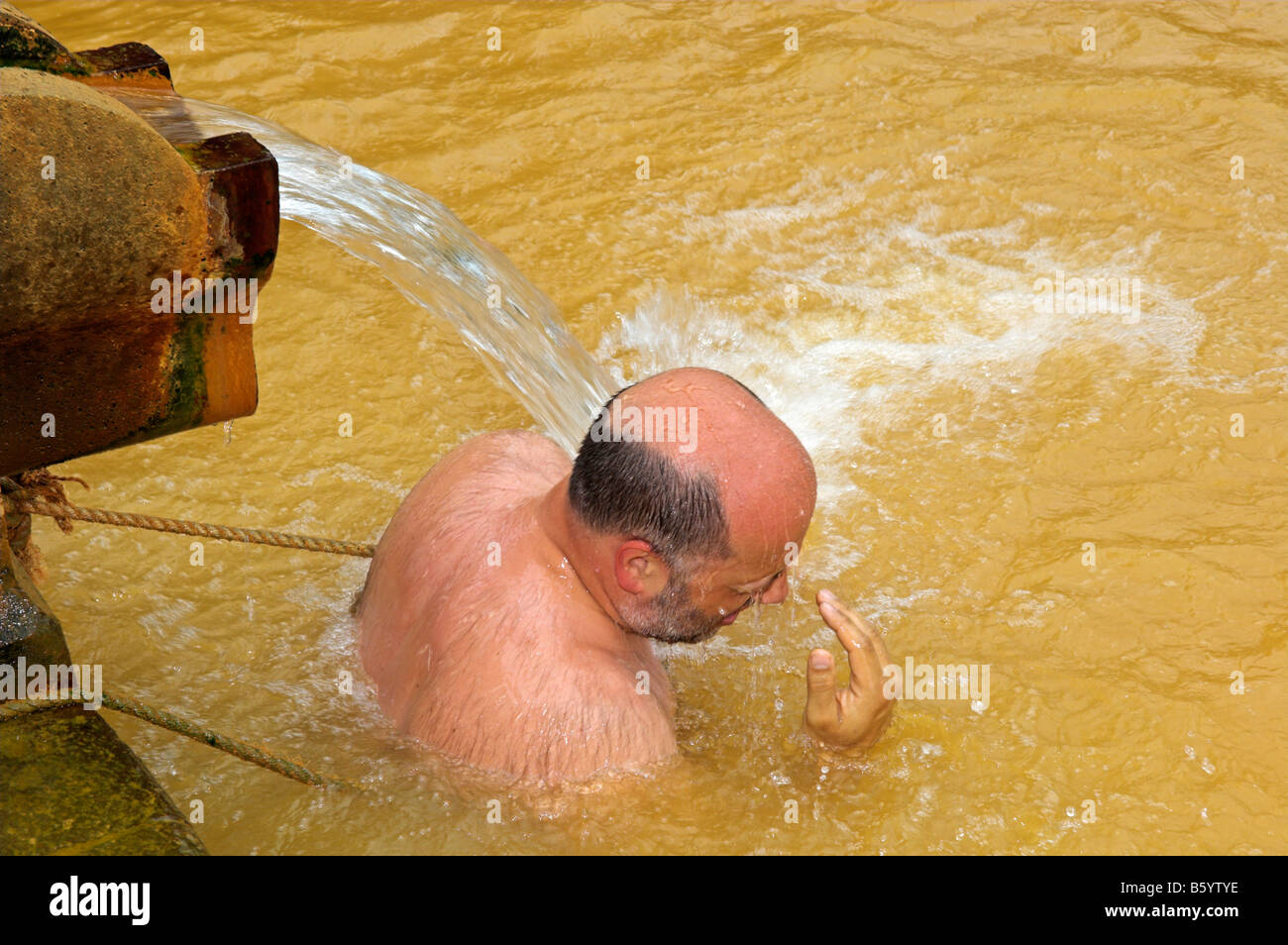 Mann unter Auslauf des thermischen heißen Mineralquelle bei Terra Nostra botanischen Garten Furnas Sao Miguel Azoren-Portugal Stockfoto
