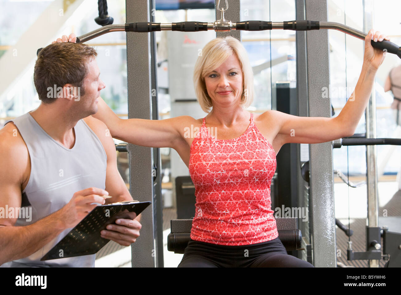 Personal Trainer beobachtete Frau Gewicht Zug Stockfoto