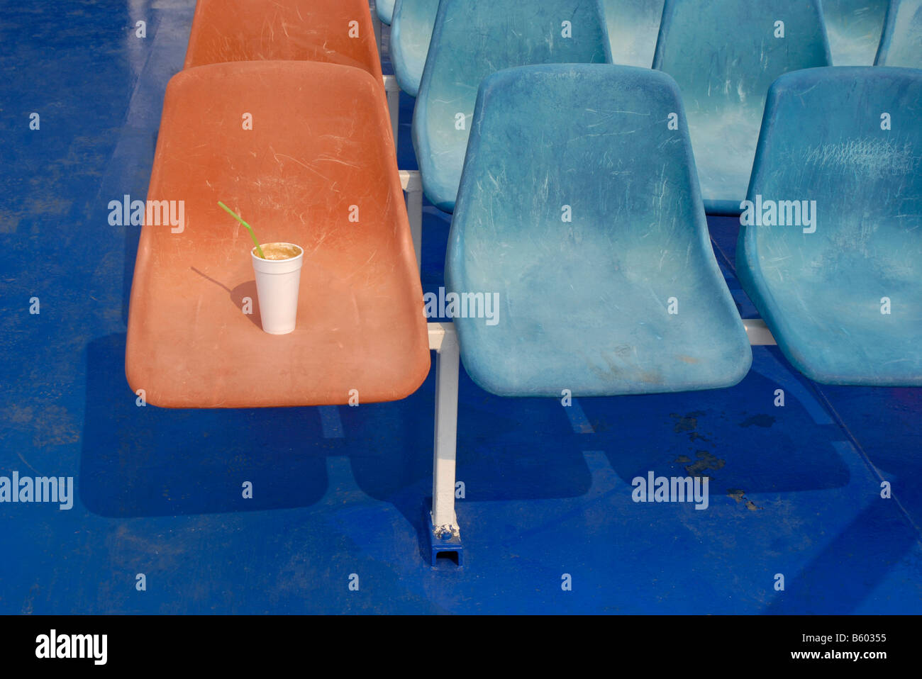 Verlassene Kaffeetasse auf Plastiksitz Stockfoto