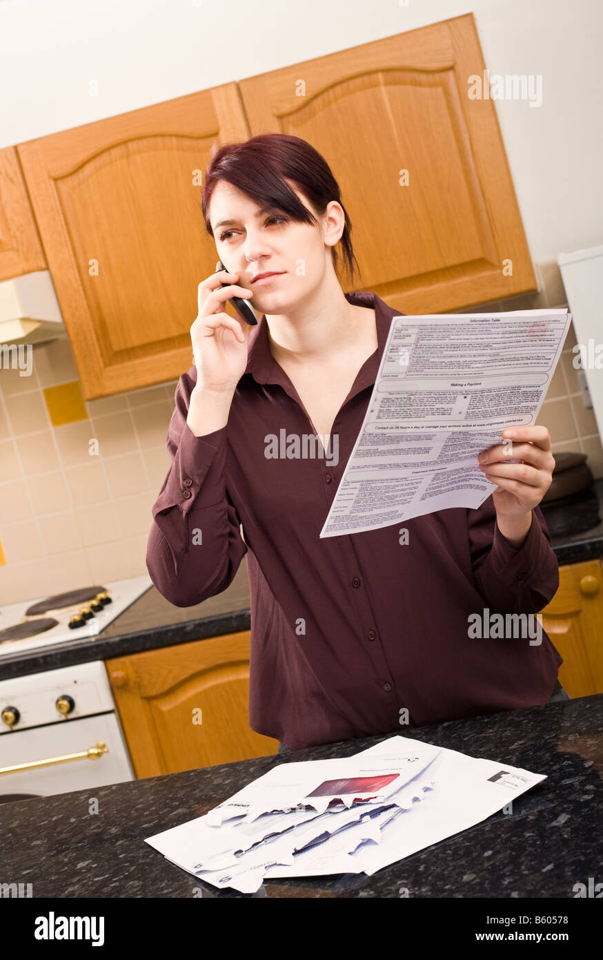 Junge Frau zu Hause Abfragen eine hohe Rechnung mit ihrem Handy hören und schauen skeptisch Herr PR Stockfoto