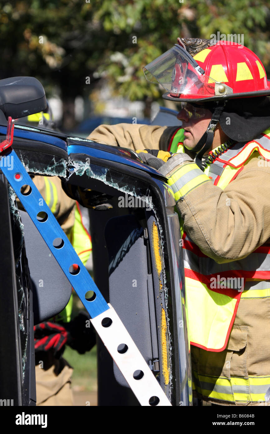 Feuerwehrmann hat das Backen des Lebens Bergung Werkzeug benutzt, um durch eine Stütze eines Autos zu schneiden, die über gerollt hat Stockfoto