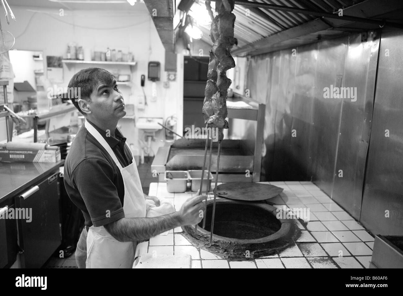 Koch in einem indischen Restaurant entfernt Kabobs aus einem hölzernen Feuer Lehmofen in New Haven Connecticut USA Stockfoto