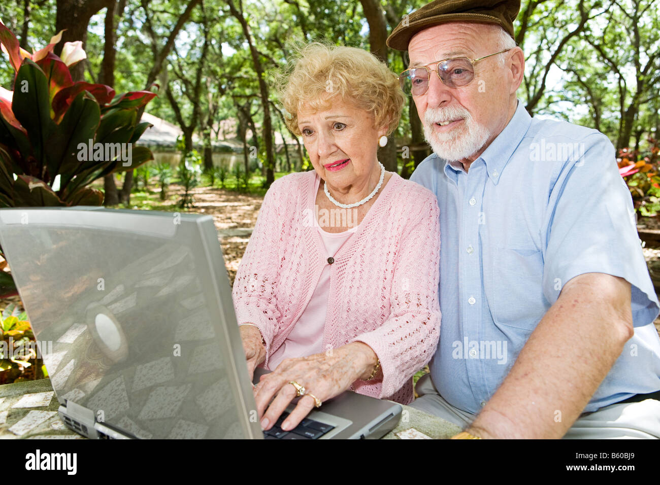 Älteres Paar mit Laptop surft im Internet in einer wunderschönen Umgebung im freien Stockfoto