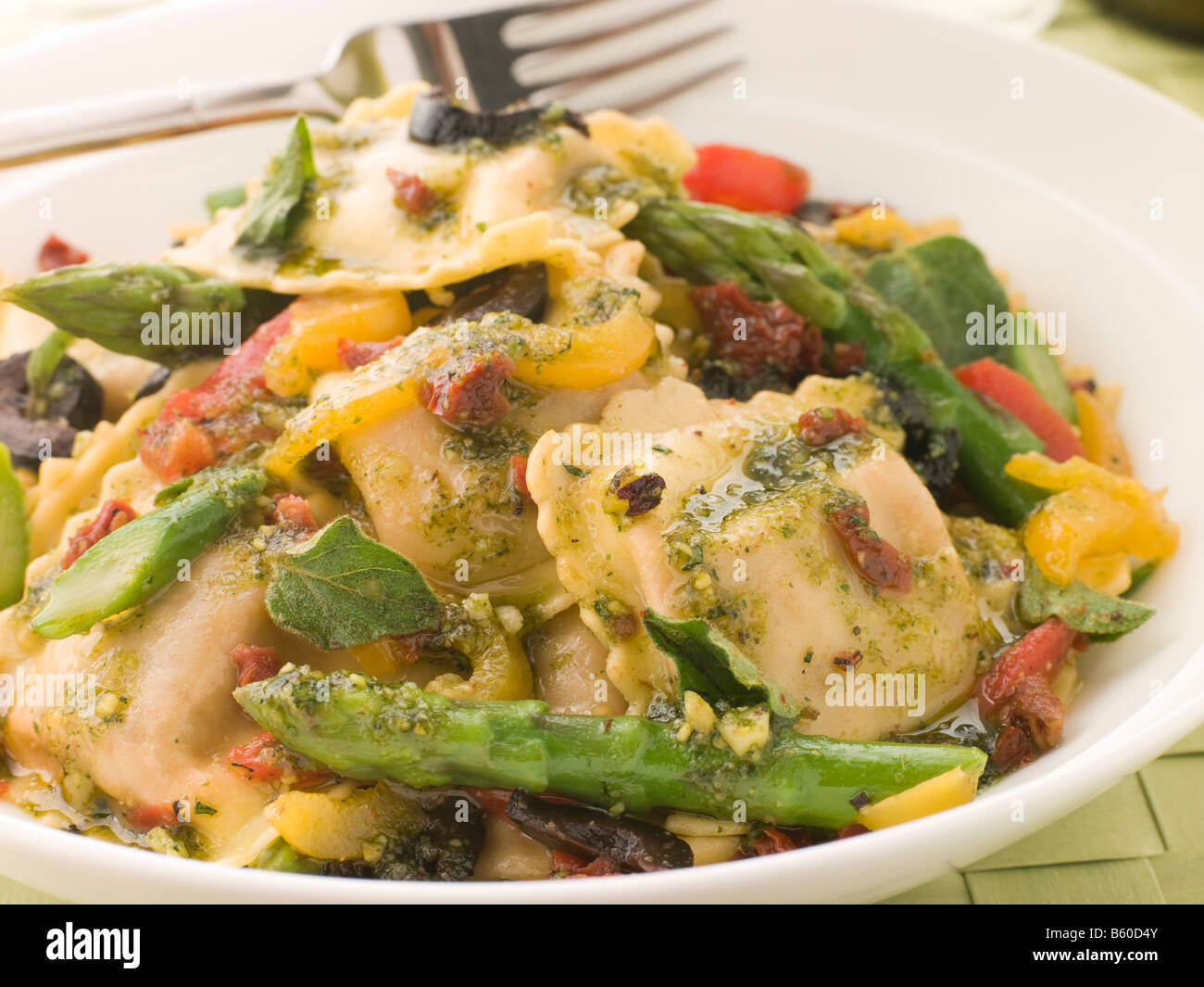 Gebratene Gemüse Ravioli mit Pesto Dressing Sonne errötete, Tomaten und Spargel Stockfoto