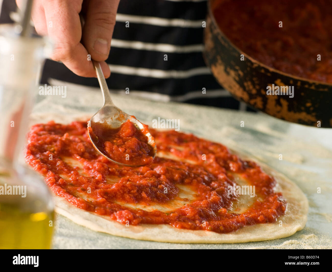 Löffel Tomatensauce auf einen Pizzateig Stockfoto