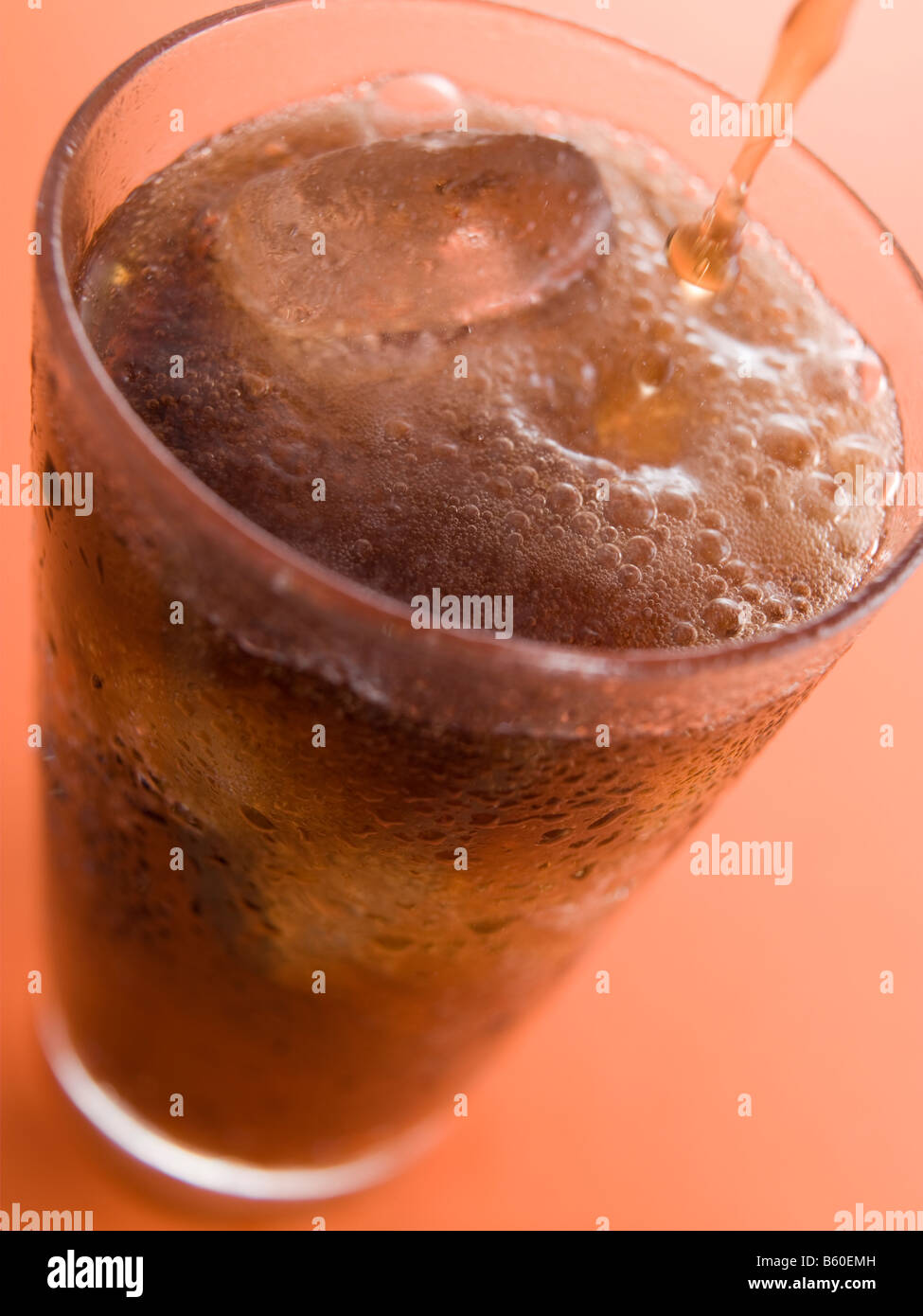 Eine Cola Gießen in ein Glas mit Eiswürfeln Stockfoto