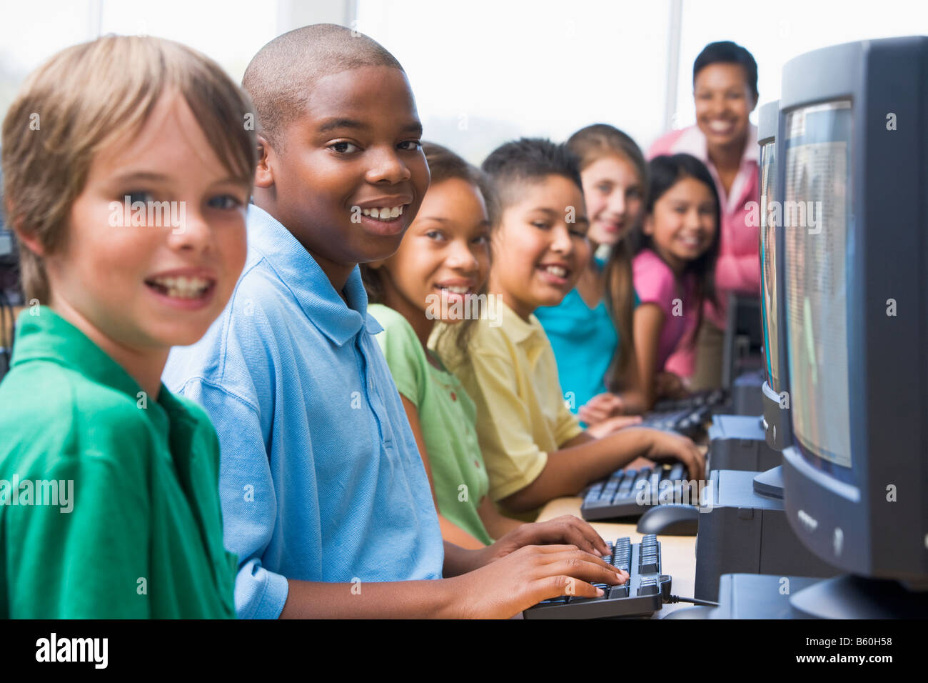 Sechs Kinder am Computer-Terminals mit Lehrer im Hintergrund (selektiven Fokus/High-Key) Stockfoto