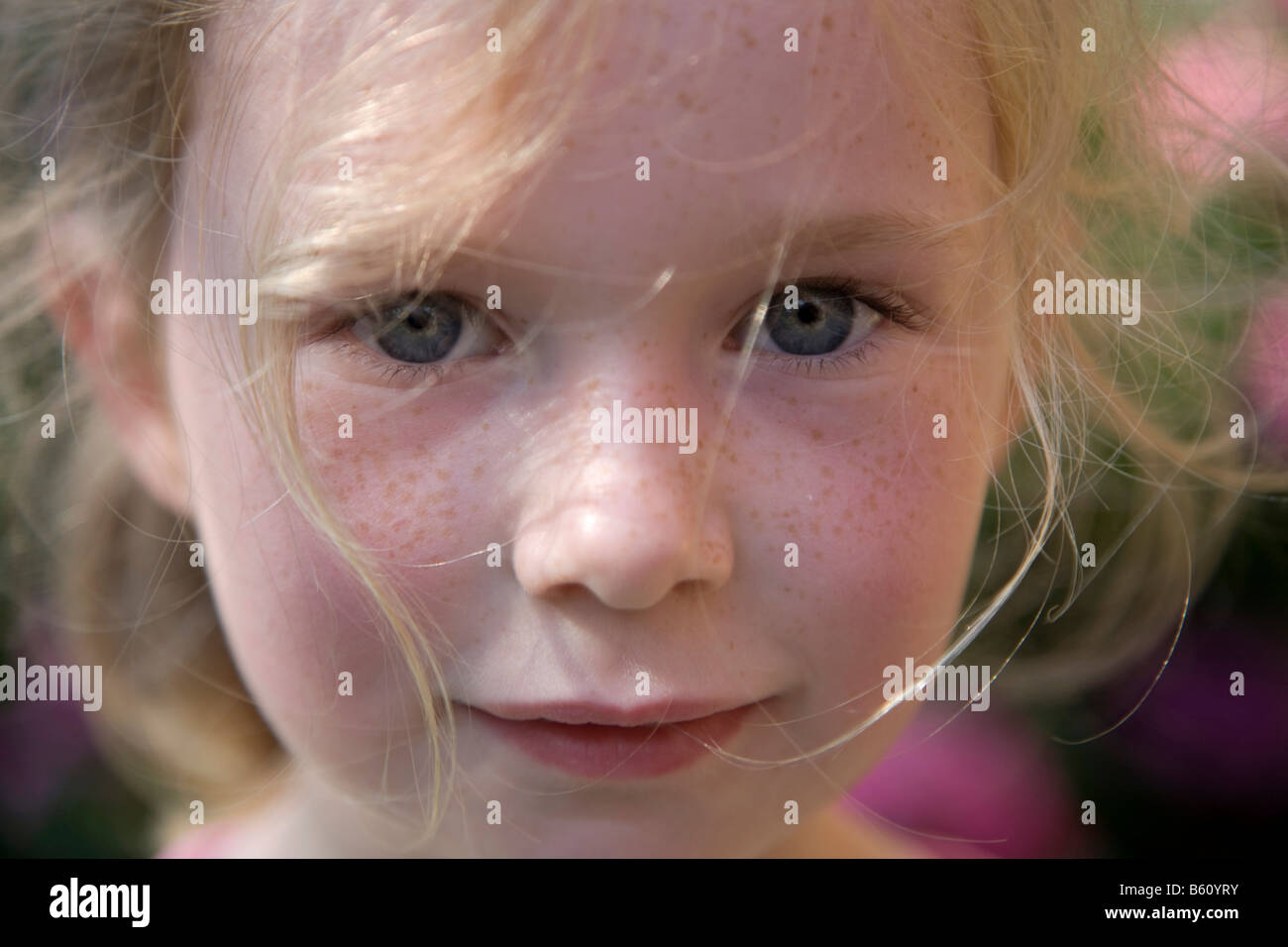 Porträt von ein sommersprossiges Mädchen, 5-10 Jahre alt, in einem Blumengarten Stockfoto