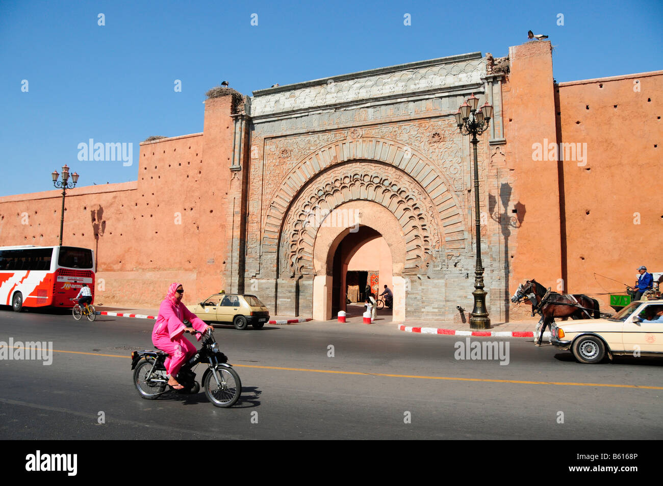 Verschleierte Autofahrerin ein Moped hinter dem Tor Bab Agnaou in Marrakesch, Marokko, Afrika Stockfoto