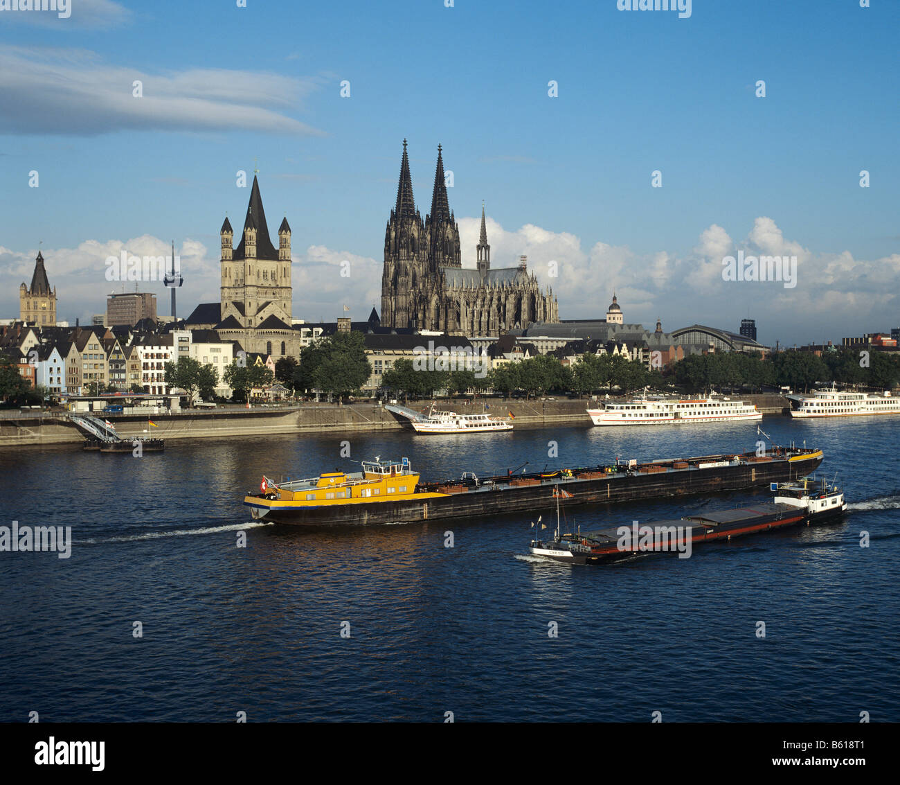 Blick über den Rhein, den Dom und die grobe St. Martin-Kirche, vorne sind Fracht Lastkähne und Touristen Boote Stockfoto