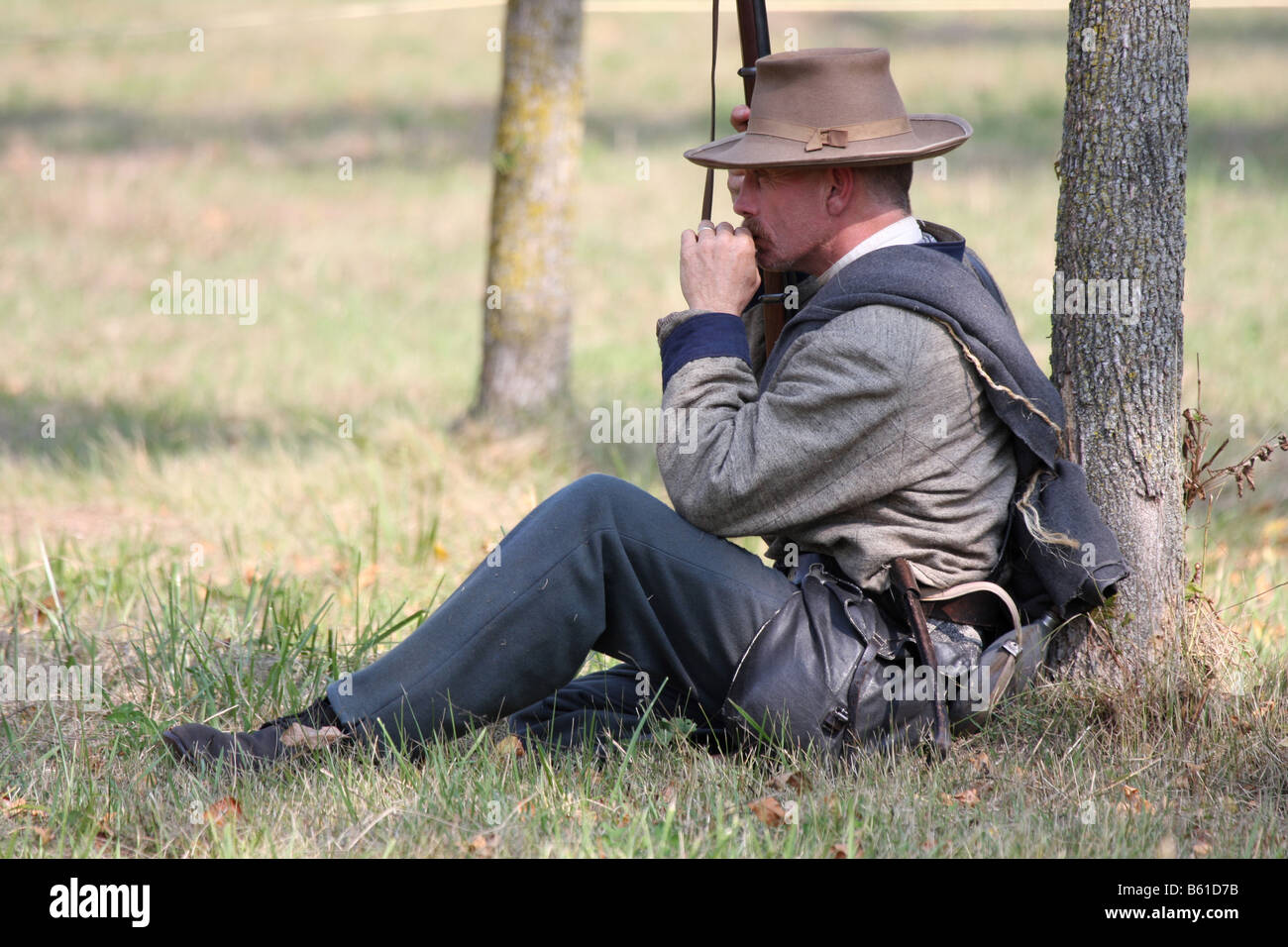 Konföderierten Bürgerkrieg Soldat lehnt sich gegen einen Baum Rauchen während einer Civil War Reenactment im alten Wade House Stockfoto