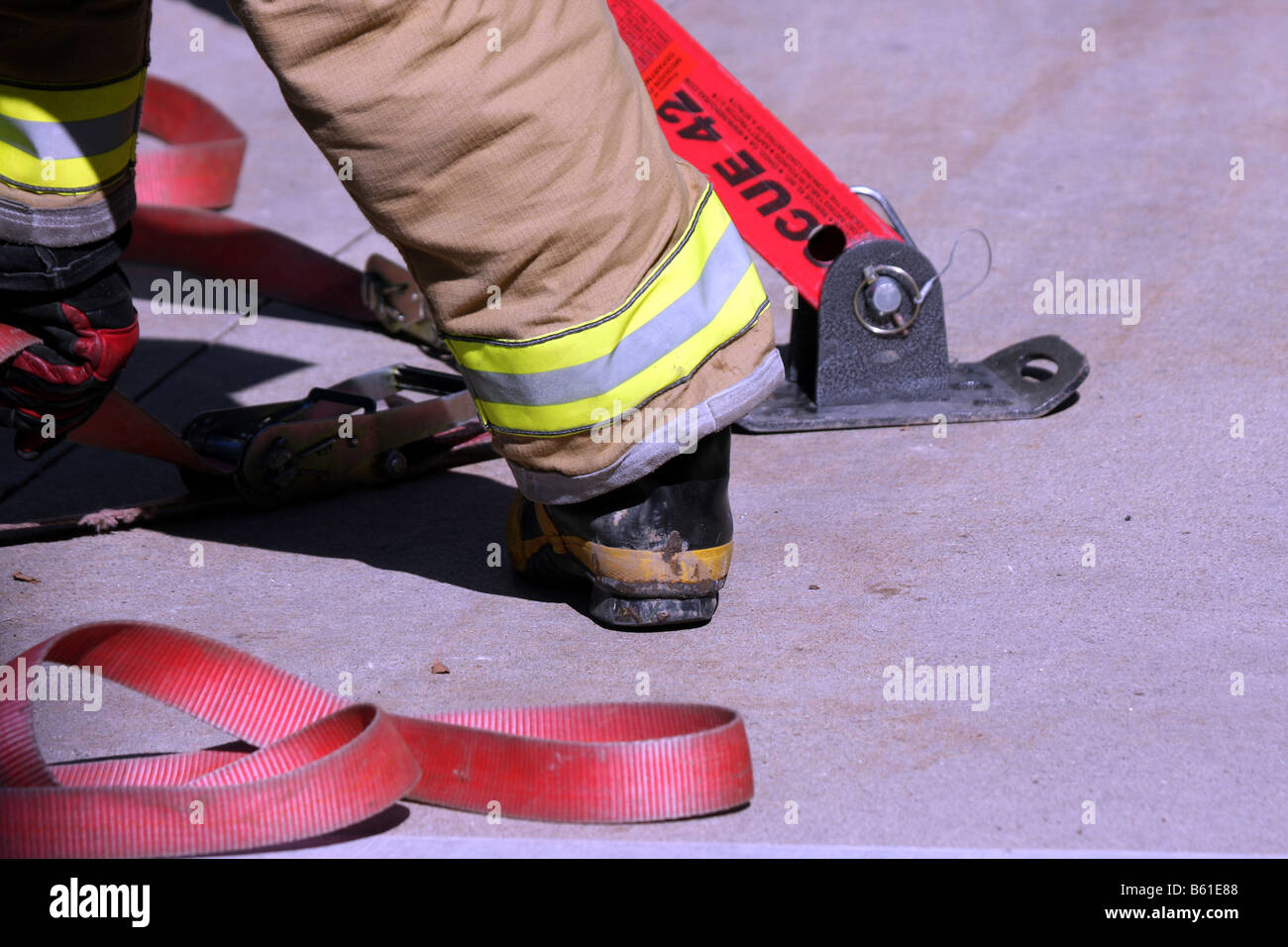 Das hintere Bein und Fuß eines Feuerwehrmannes mit Bar und Gurte, um ein Fahrzeug zu stabilisieren, die bei einem Unfall überrollt hat Stockfoto