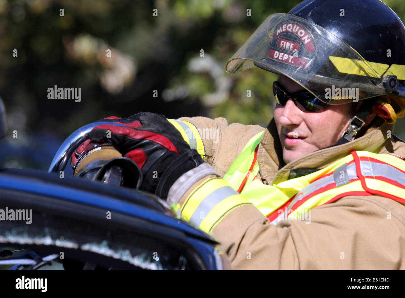 Ein Feuerwehrmann mit Jaws Of Life-Tool arbeiten Bergung auf einem Auto zu tun, die auf die Seite, über gerollt hat Stockfoto