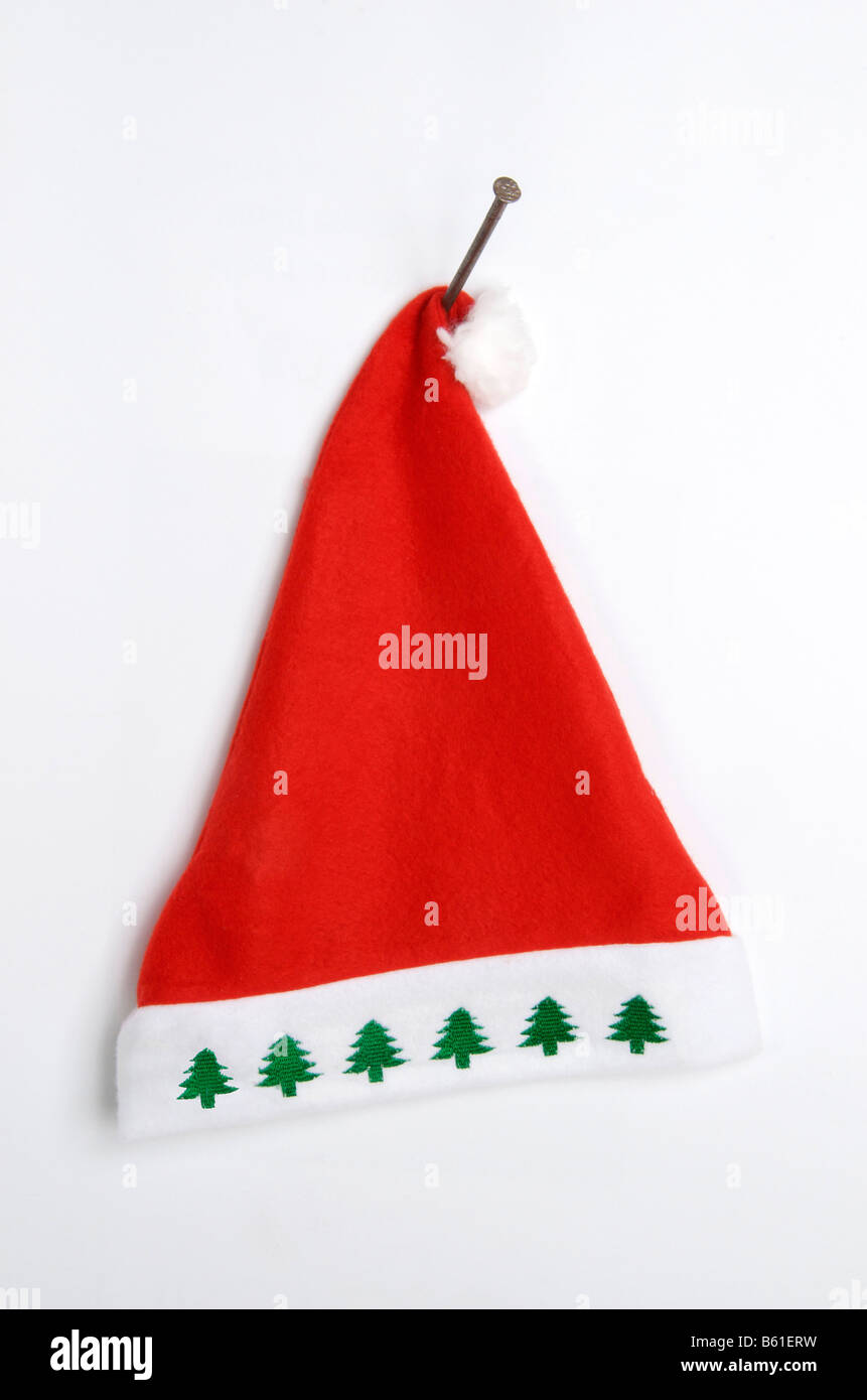 Rote Weihnachtsmütze mit weißem und grünem Design, die an einem Wandhaken zur festlichen Dekoration aufgehängt wird Stockfoto