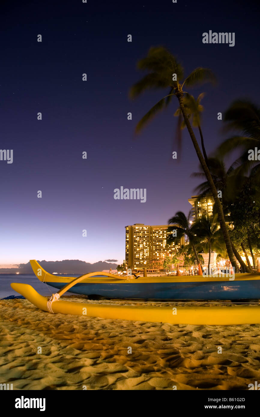Ein Ausleger-Kanu am Strand von Waikiki in Honolulu, Oahu, Hawaii in der Abenddämmerung. Stockfoto