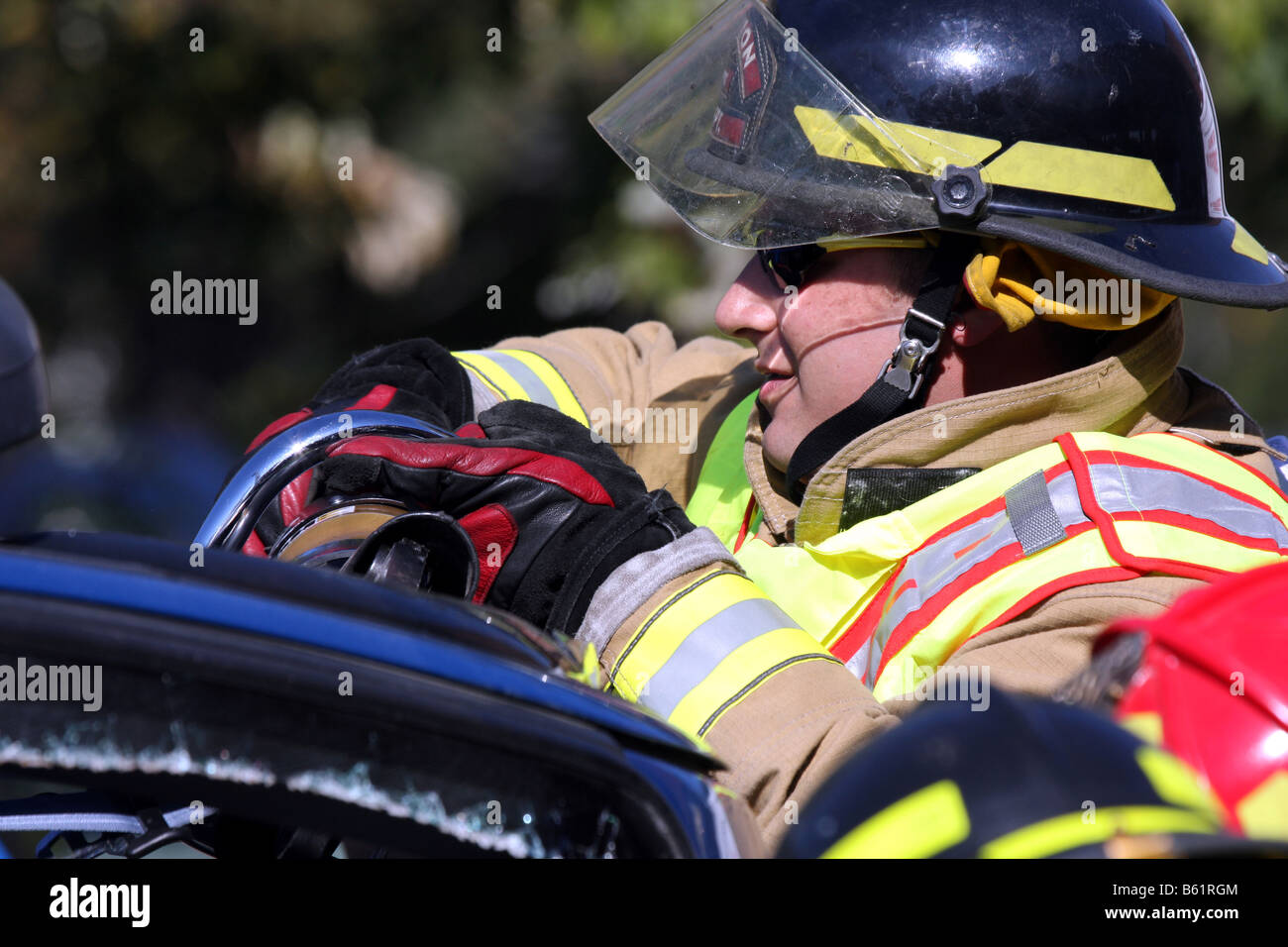 Ein Feuerwehrmann mit Jaws Of Life-Tool arbeiten Bergung auf einem Auto zu tun, die auf die Seite, über gerollt hat Stockfoto