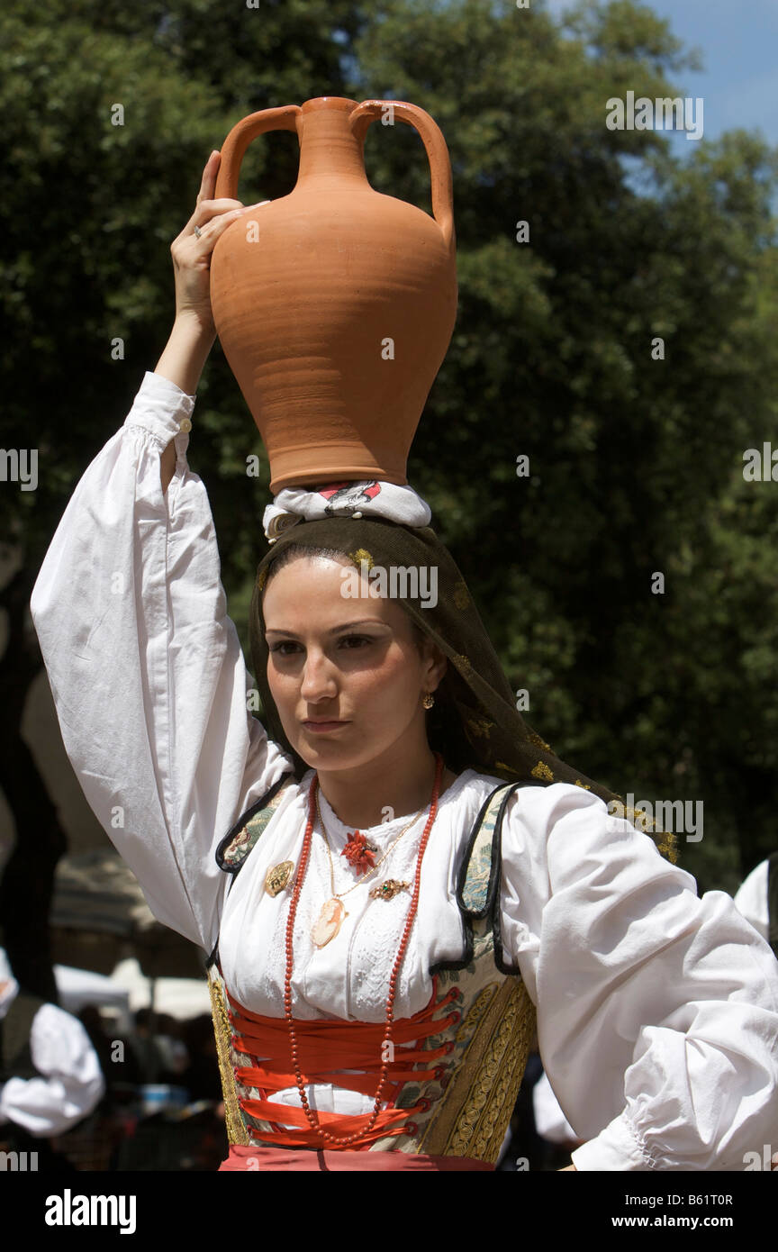 Junge Frau trägt Tracht tragen eine Amphore auf dem Kopf beim Cavalcata Sarda Festival in Sassari, Sardinien, Italien Stockfoto