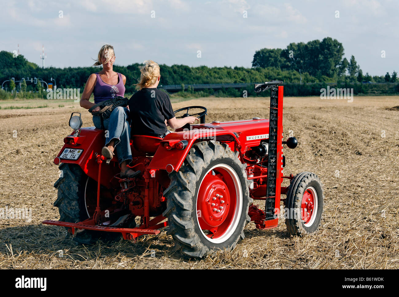 Zwei blonde Frauen auf einem Oldtimer-Traktor Mc Cormick, Erntefest Angermunder Treckerfreunde, Düsseldorf, Nordrhein-Westfalen, G Stockfoto