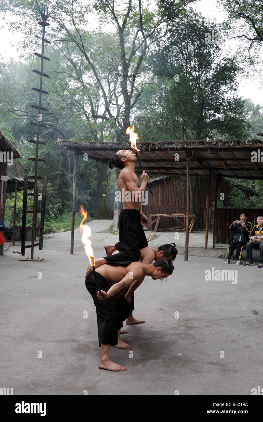 Chinesische Miao ethnischen Minderheit der jungen Männer die traditionelle Feuer Straßenmusik durch das Lecken und schlucken Flammen Touristen zu unterhalten Stockfoto