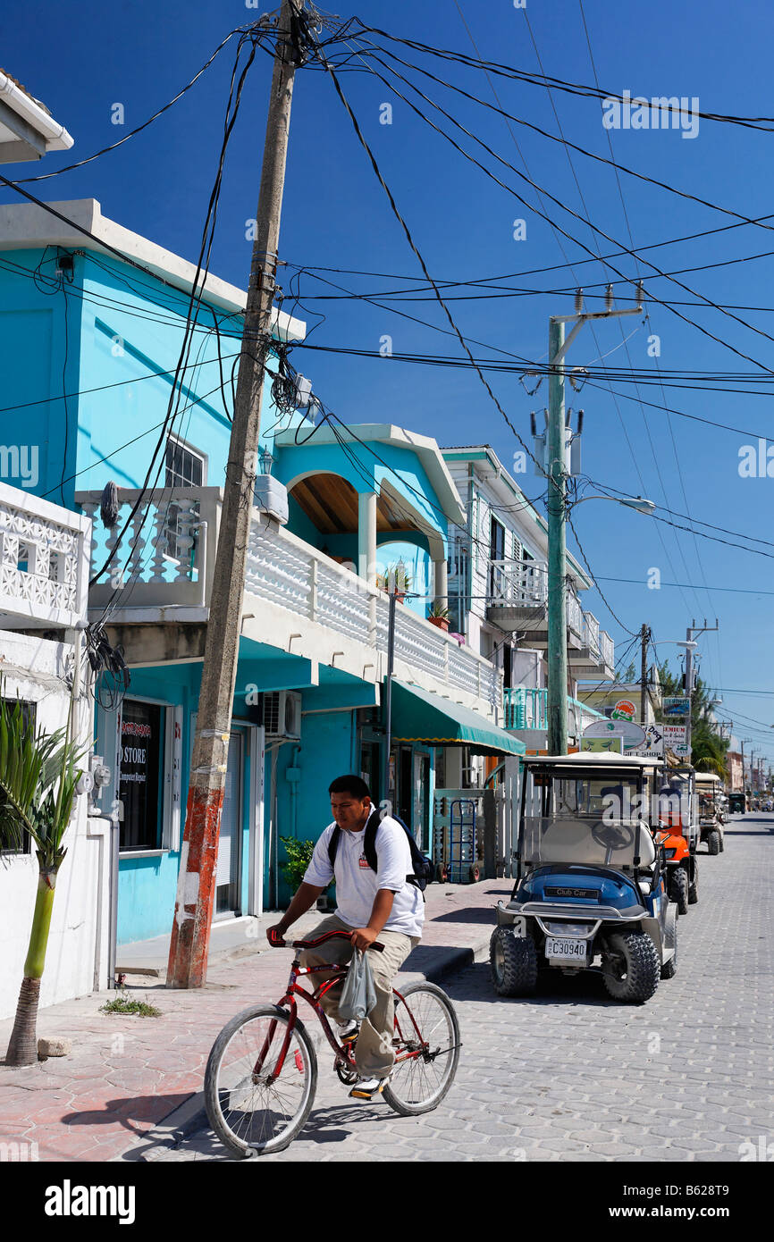 Web von Freileitungen auf der Hauptstraße über ein Fahrrad, Holzhäuser und Golf-Cart, San Pedro, Ambergris Cay Insel, Belize, Stockfoto