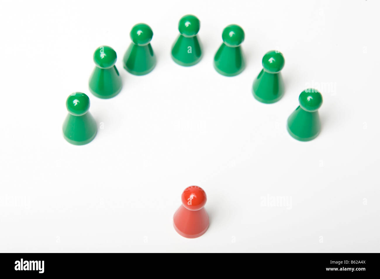 Grünen Spielsteine stehen um einen einzigen roten Stein, symbolisch für eine Rede oder coaching Stockfoto