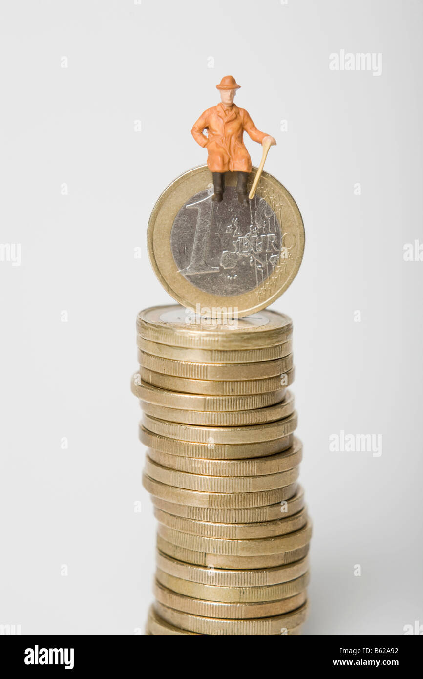 Rentner-Figur sitzt auf einem Stapel von Euro-Münzen, symbolisch für den Ruhestand Stockfoto