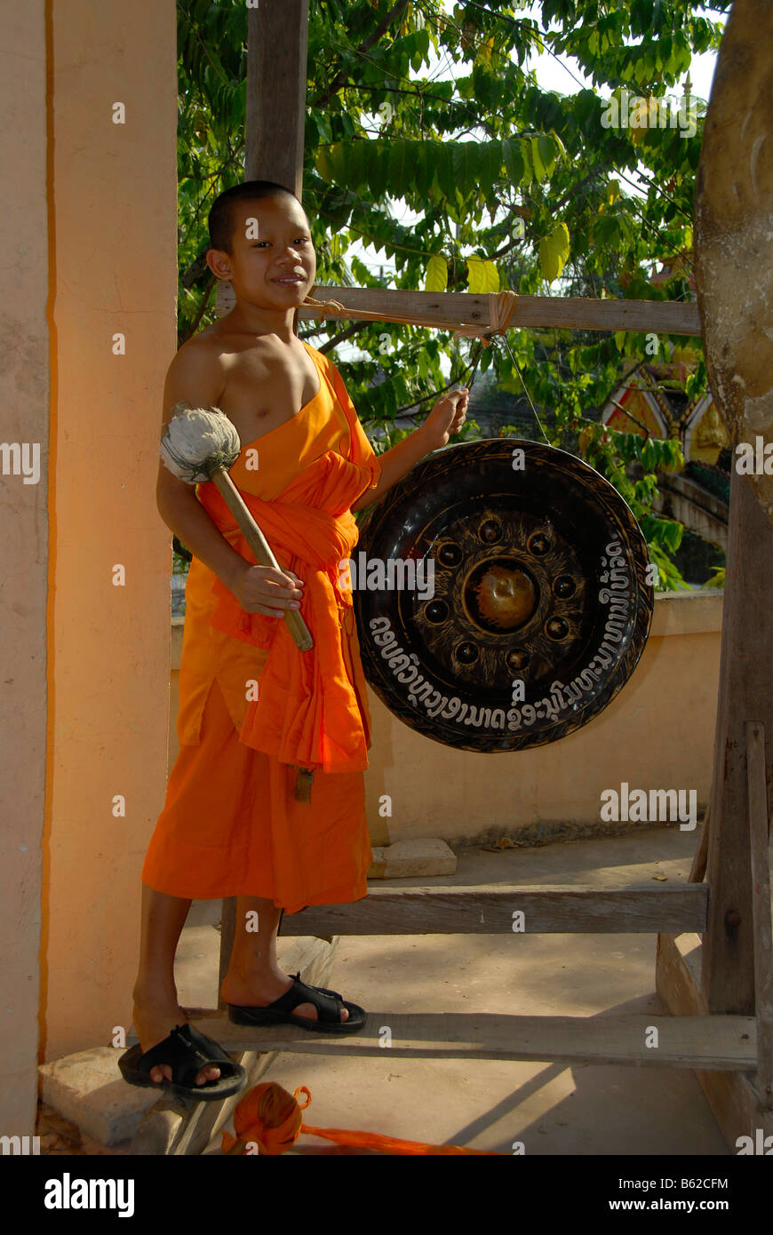 Buddhistischer Novize trägt einen orangefarbenen Gewand einen Gong schlagen, Wat Phonxay, Vientiane, Laos, Südostasien Stockfoto